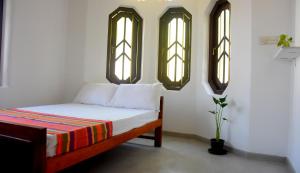 Un dormitorio con una cama y dos ventanas. en Villa Weligama Gedara, en Weligama