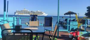 a cruise ship on the water with a table and chairs at Victoria s Beach House and Snorkeling Center in Roatan