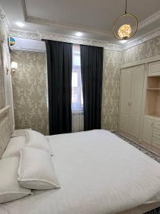 um quarto com uma grande cama branca e uma janela em Квартира Самарканд em Samarcanda