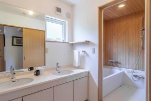a bathroom with two sinks and a tub and a mirror at Chalet Murasaki in Niseko