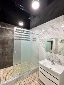 La salle de bains est pourvue d'une douche en verre et d'un lavabo. dans l'établissement Квартира Самарканд, à Samarcande