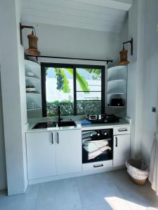 a white kitchen with a sink and a window at Tropical Bali Style House with Kitchen outside and Shared Pool in Salad Beach