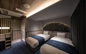 ein Hotelzimmer mit zwei Betten und einem Fernseher in der Unterkunft Dotonbori Hotel in Osaka