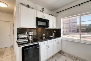 a kitchen with white cabinets and a black counter top at Best Location SOBE Top Floor 2 min to beach & fun in Miami Beach