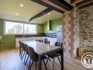 - une cuisine avec une table à manger et des chaises dans l'établissement Gîte de charme avec terrasse, près de Nantes, campagne des Mauges, idéal pour familles et pêcheurs - FR-1-622-73, à La Jactrie