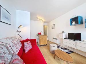 ein Wohnzimmer mit einem roten Sofa und einem Fernseher in der Unterkunft Studio cozy à La Daille, accès direct pistes, balcon, ascenseur - FR-1-518-158 in Val dʼIsère