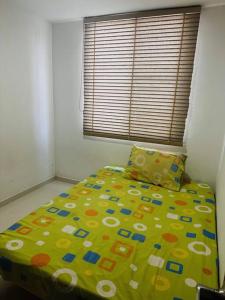 Cali Valle del Lili Apartamento في كالي: غرفة نوم بسرير مع لحاف اصفر ونافذة