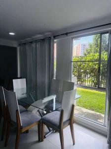 Cali Valle del Lili Apartamento في كالي: غرفة طعام مع طاولة زجاجية وكراسي ونافذة
