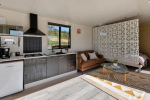 a kitchen and living room with a couch and a table at Valley View - Whangarei Tiny Home in Whangarei