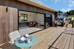 a wooden deck with a table and a patio at Valley View - Whangarei Tiny Home in Whangarei