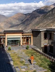 a man walking past a building with mountains in the background at Shinta Mani Mustang in Jomsom