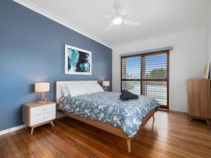 a bedroom with a bed and a blue wall at Beach House on Pearl - Kingscliff Central in Kingscliff