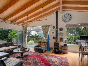Una sala de estar con un sofá y un reloj en la pared. en Kiwi Charmer - Onemana Holiday Home, en Opoutere