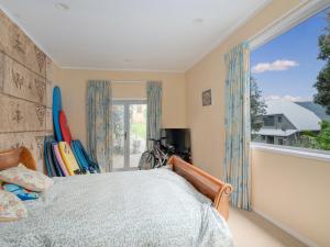 Un dormitorio con una cama y una ventana grande. en Kiwi Charmer - Onemana Holiday Home, en Opoutere