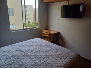 1 dormitorio con 1 cama, TV y escritorio en Habitación acogedora Orué en Lima
