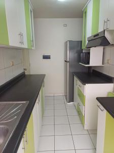 a kitchen with green and white cabinets and a refrigerator at Habitación acogedora Orué in Lima