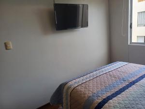 1 dormitorio con 1 cama y TV de pantalla plana en la pared en Habitación acogedora Orué en Lima