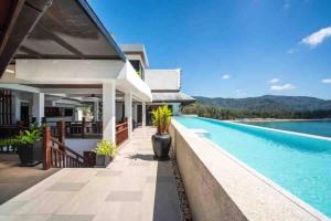 a house with a swimming pool next to the water at Lang- Villa Amara，Kamala beach luxury villa in Surin Beach