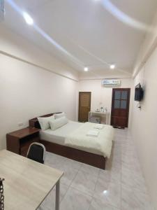 a bedroom with a bed and a table in it at เอส ที อพาร์ทโฮเทล / S.T.ApartHotel in Ban Khao Rup Chang