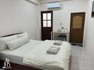 a bedroom with a bed with towels on it at เอส ที อพาร์ทโฮเทล / S.T.ApartHotel in Ban Khao Rup Chang
