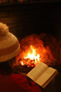 un livre et un chapeau près d'un feu dans l'établissement Kasar Himalaya Holiday Home, Binsar Rd, à Almora
