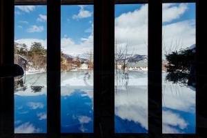 白馬的住宿－Hakuba Pension & Log Hotel Meteor，窗户享有雪覆盖的庭院的景致。