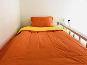 ein Bett mit einer orangefarbenen Decke auf einem Zimmer in der Unterkunft Best Room In Kawagoe 3 in Kawagoe