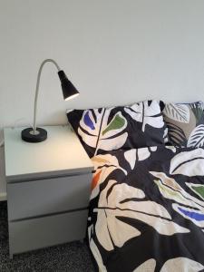 a lamp on a night stand next to a bed at Rent Entire Calmhaven Apartment in Nottingham
