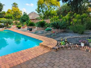 a swimming pool in a yard with a brick walkway around it at Wilger Guesthouse - Self-Catering Business Accommodation in Centurion in Centurion