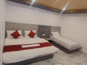 Schlafzimmer mit einem Bett mit roten und weißen Kissen in der Unterkunft RUPALI GUEST HOUSE in Badrīnāth