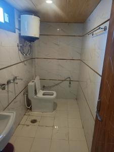 a small bathroom with a toilet and a sink at RUPALI GUEST HOUSE in Badrinath