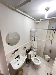a bathroom with a toilet and a sink and a mirror at Cozy 2-BR in UDH, Manila in Manila