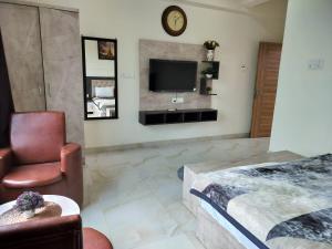 Hotel Dawat في Pura Raghunāth: غرفة نوم بسرير وتلفزيون وكرسي