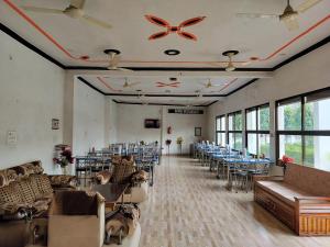 a banquet hall with tables and chairs and windows at Hotel Dawat in Pura Raghunāth