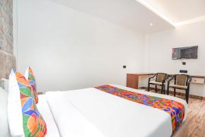 a bedroom with a bed and a table and chairs at FabHotel The Comfort Inn in Kānpur