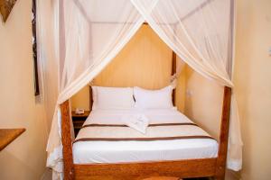 a bedroom with a canopy bed with white sheets at The Island Stone Town hotel in Stone Town