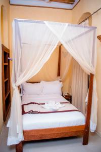 1 dormitorio con 1 cama con dosel en The Island Stone Town hotel, en Ngambo