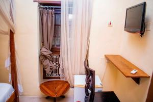 a room with a window with a desk and a television at The Island Stone Town hotel in Stone Town