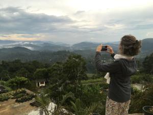 a woman taking a picture of the mountains with a camera at Adisham village home in Haputale