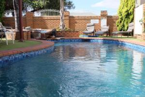 a swimming pool with chairs and a brick wall at Charles sturt motor inn in Cobram