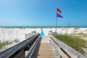 un chemin en bois menant à la plage avec un drapeau dans l'établissement Phoenix-VII Unit 7814 - NEW-Beach front-Sleeps 6, à Orange Beach