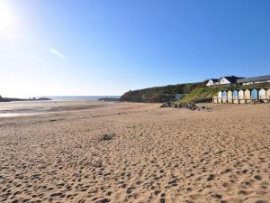 a sandy beach with a row of houses on it at 3 Bed in Bude PORTH in Morwenstow