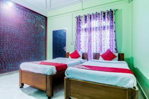 two twin beds in a room with a window at OYO Flagship Bonfire Kaziranga Resort in Kāziranga