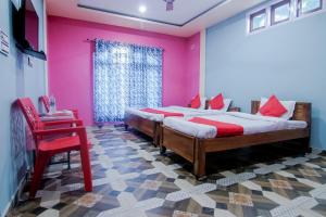 1 dormitorio con 2 camas y pared de color rosa en OYO Flagship Bonfire Kaziranga Resort, en Kāziranga