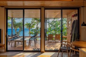 a dining room with glass doors and a table and chairs at ガーデンヴィラ白浜　KOTI in Shimoda