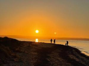 a group of people standing on a beach at sunset at Homey Beach Cottage with Spa, walk to beach in Cowes