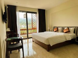 a bedroom with a bed and a large window at Dongvan Ville Du H'Mong Hotel in Dồng Văn