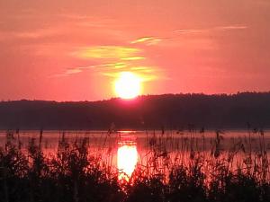 una puesta de sol sobre un cuerpo de agua con un barco en Auszeit am See, en Dahmen