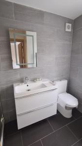 a bathroom with a sink and a toilet and a mirror at NEW! Brand New Beautiful Modern Apartment in London