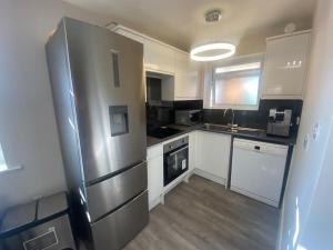 Il comprend une cuisine équipée d'un grand réfrigérateur en acier inoxydable. dans l'établissement NEW! Brand New Beautiful Modern Apartment, à Londres